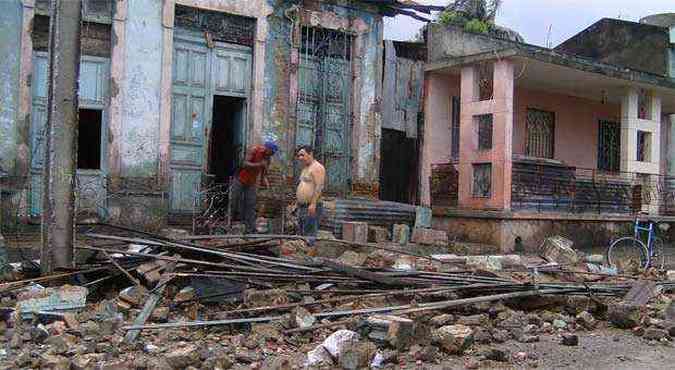 Homens limpam destroos de parte de uma casa que cedeu durante a passagem do furaco Sandy(foto: AFP PHOTO/AIN-Ariel SOLER CASTAFREDA )