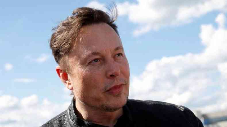Elon Musk olhando para o lado, sob cu azul