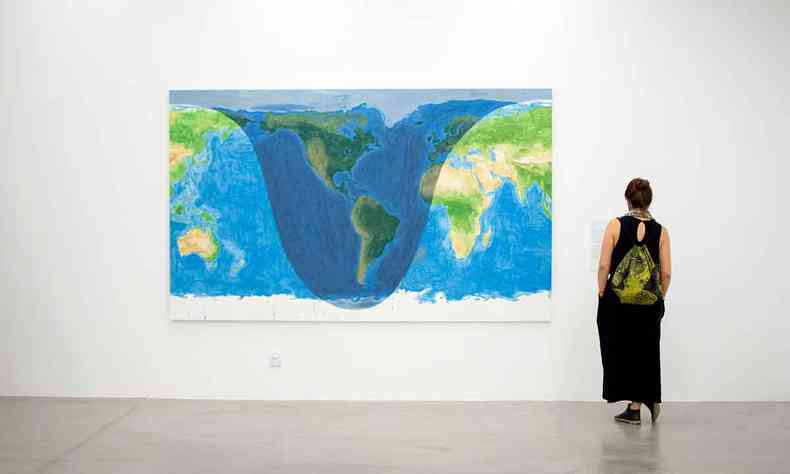 Mulher vê quadro de Jorge Macchi com imagem que remete ao mapa mundi, com as Américas dentro de uma cavidade