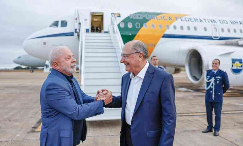 Lula e Alckmin fazem aperto de mos diante de avio que vai levar Lula para a China