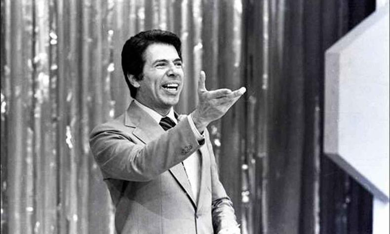 O apresentador Silvio Santos sorri e levanta a mo durante seu programa