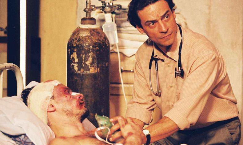 Ator Enrique Diz est deitado na cama, doente, e Luiz Carlos Vasconcelos como o mdico com o respirador na mo em cena na enfermaria no filme Carandiru