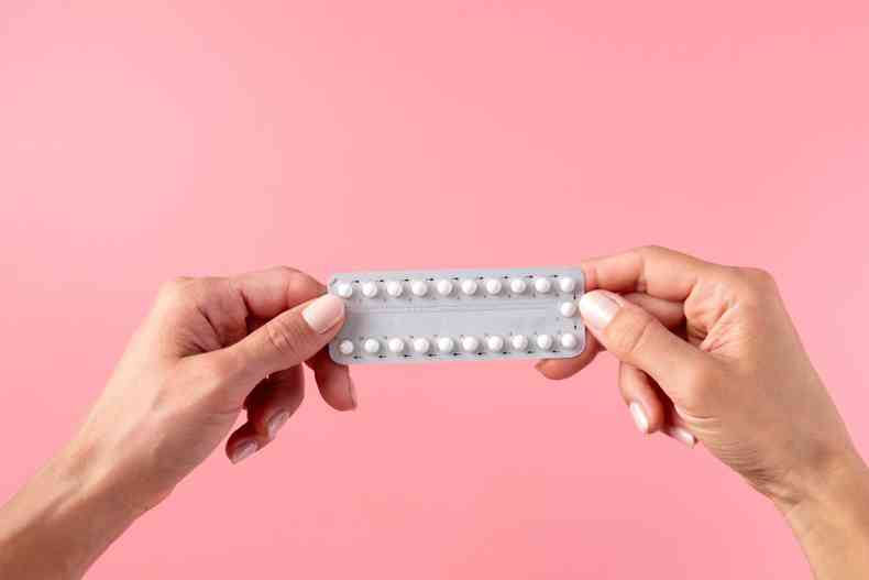 Mulher segurando uma cartela de anticoncepcional 