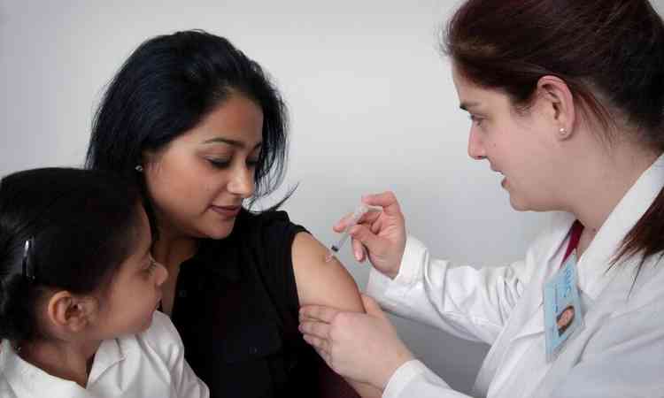 mulher recebe vacina com a filha no colo