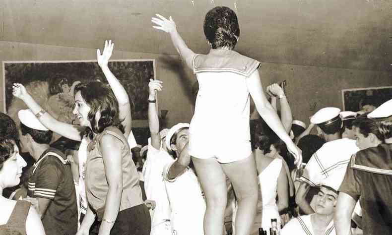Mulher, de costas para a cmera, dana em cima da mesa cercada de folies fantasiados de marinheiro no baile de carnaval realizado no Iate Tnis Clube, em BH, em 1963