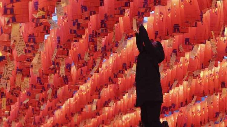 Visitante pendura lanterna de papel vermelho com desejos de Ano Novo durante um show de lanternas na antiga muralha da cidade de Xian, na China