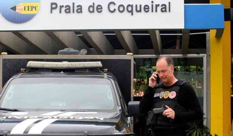 Policial civil em frente  fachada da escola Praia do Coqueiral.