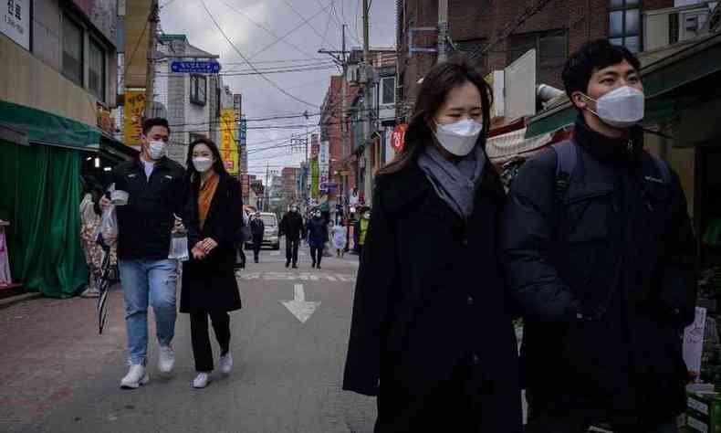 Casais com mscaras andam em rua comercial de Seul em meio s preocupaes com a COVID-19(foto: Ed JONES / AFP)