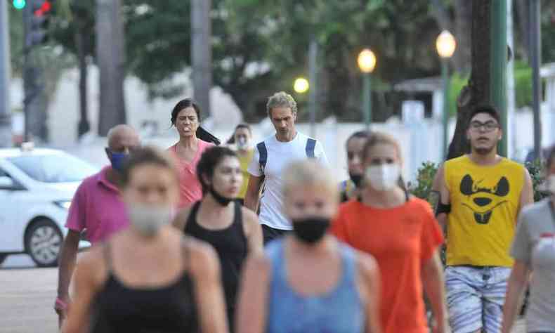 Pessoas caminham na Praça da Liberdade, a maioria delas usando máscaras