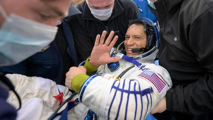Frank Rubio, um homem de pele clara, em roupa de astronauta, sendo transportado por outras pessoas