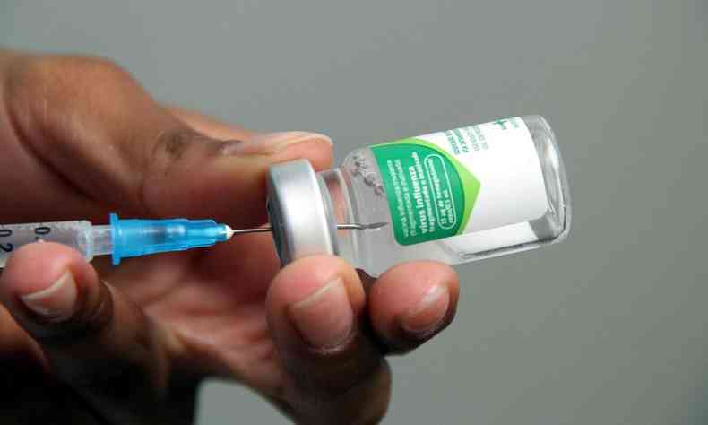 Mo segurando seringa e frasco da vacina