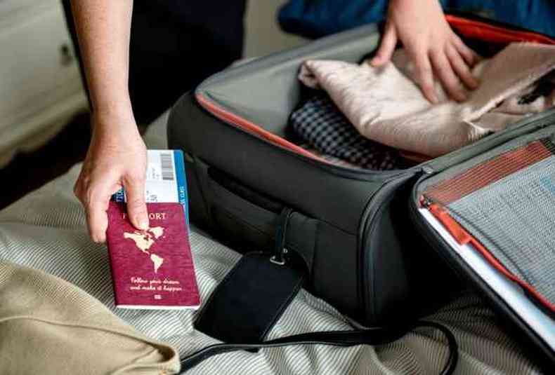 Pessoa arrumando a mala com passaporte na mo