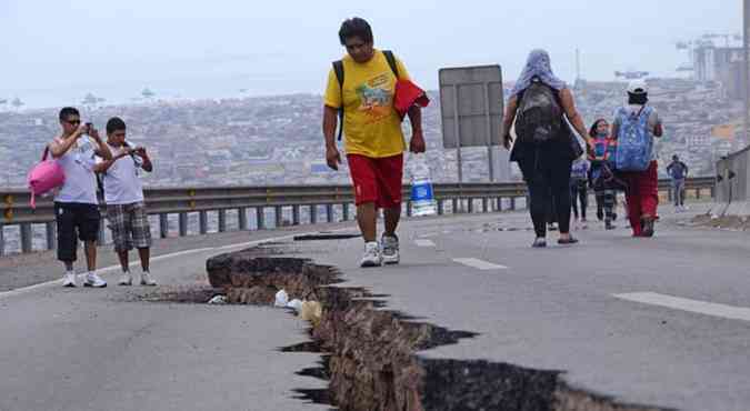 Moradores de Iquique passam por estrada danificada pelo terremoto que atingiu a cidade na noite de tera-feira(foto: AFP PHOTO / ALDO SOLIMANO)