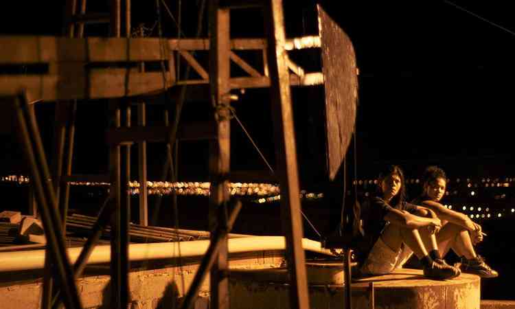 Duas mulheres sentadas  noite em estrutura parecida com torre em cena do filme ''Mato seco em chamas''