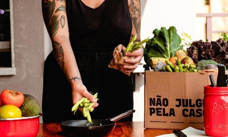 mulher coloca legumes na panela