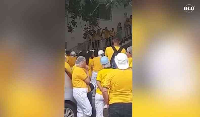 Print do vdeo, trabalhadores com camiseta amarela, homem falando ao fundo.