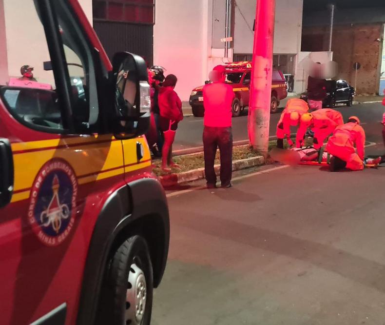 Motociclista de 20 anos acabou batendo de frente contra o poste. Foi socorrido com muitos ferimentos no rosto e confuso Bombeiros prestam atendimento motoboy bateu em poste cado no asfalto em Alfenas