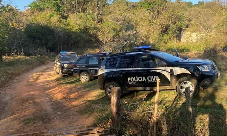 Viaturas da Polcia Civil em acostamento de estrada de terra. 