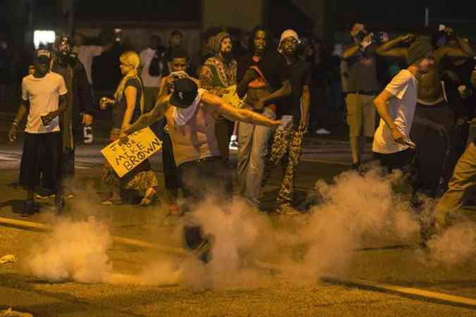 Manifestante chuta bomba de gs lacrimogneo para a polcia em protesto pelo assassinato de jovem negro, em Ferguson, no Missouri (foto: AFP Photo)