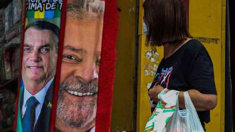 Mulher com sacola de compras observa toalhas estampadas com rostos de Lula e Bolsonaro