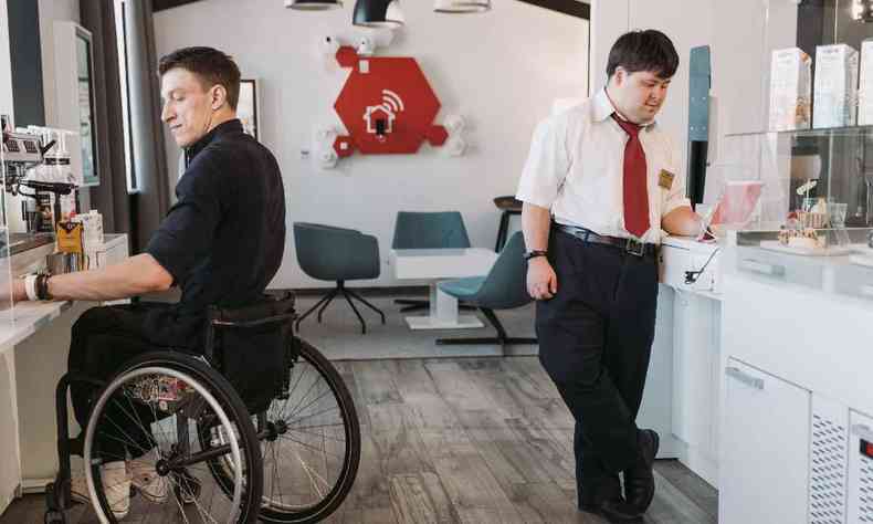 Um cadeirante e uma pessoa portadora de Síndrome de Down trabalhando