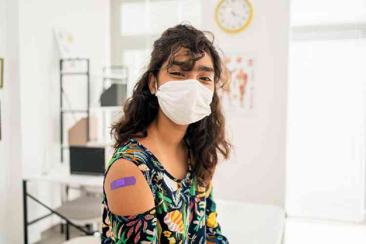 adolescente usando máscara e com curativo pós-vacina no braço