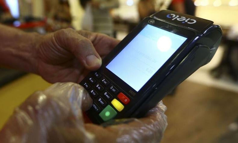 Pessoa usa mquina de cartes de crdito e dbito 