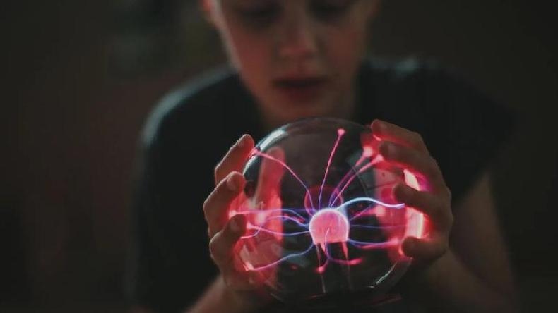 Criana segurando um globo de plasma