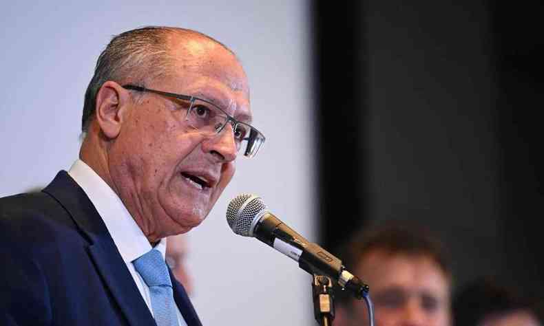 Geraldo Alckmin, falando em frente a um microfone. Um homem calvo de terno e oculos