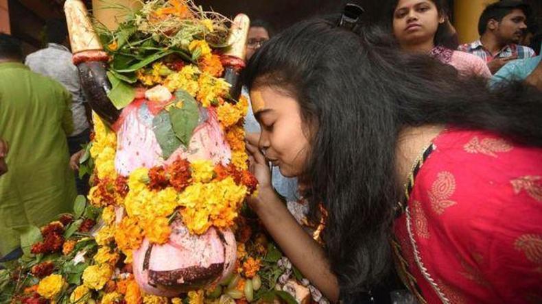 Mulher fazendo referncia a objeto de culto, rodeado de flores