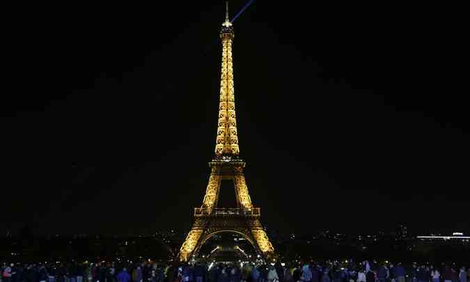 As pessoas ficam na frente da Torre Eiffel antes de as luzes serem desligadas durante a Hora do Planeta, em Paris(foto: AFP / Zakaria ABDELKAFI)