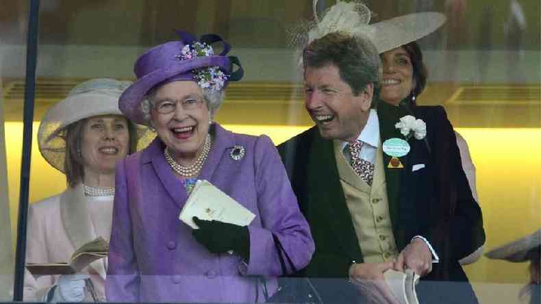 A rainha Elizabeth 2 e John Warren com sorrisos abertos e em p em camarote