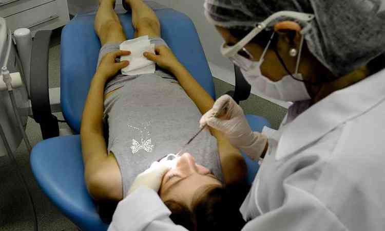 Dentista tratando os dentes de uma jovem