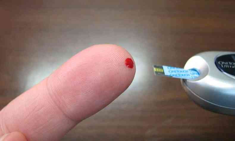 Diabtico pica o dedo com aparelho usado para medir insulina no sangue 