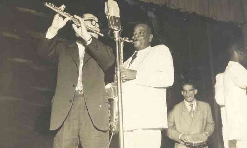 O flautista Benedito Lacerda e Pixinguinha durante show, em frente ao microfone