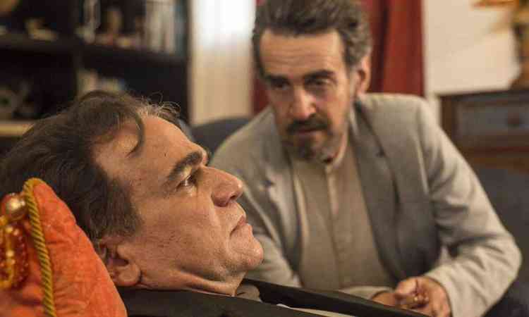 O ator  Eduardo Moreira est deitado no div observado pelo ator Renato Parara em cena do filme O lodo