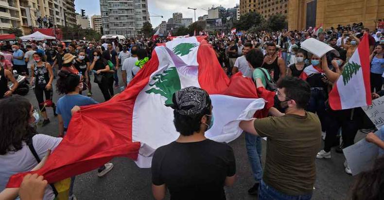 Com uma grande bandeira do Líbano, uma multidão de manifestantes saiu pelas ruas de Beirute protestando contra a classe política(foto: STR/AFP) Com uma grande bandeira do Líbano, uma multidão de manifestantes saiu pelas ruas de Beirute protestando contra a classe política(foto: STR/AFP)