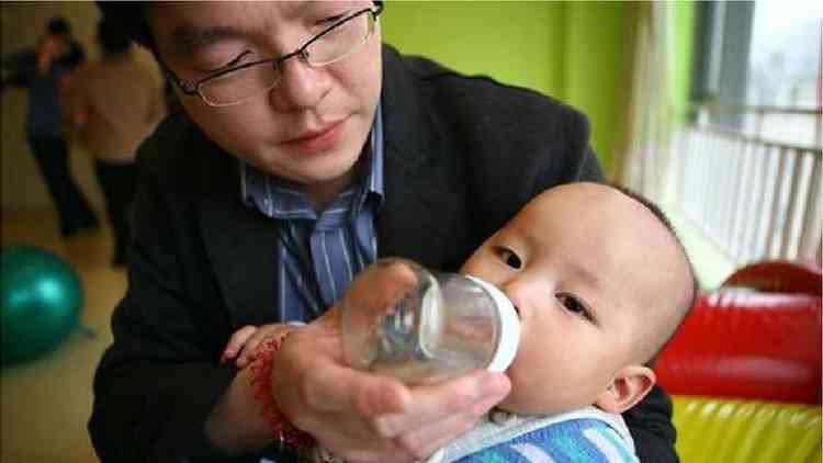 Pai alimenta seu filho com mamadeira na pré-escola em Pequim, na China