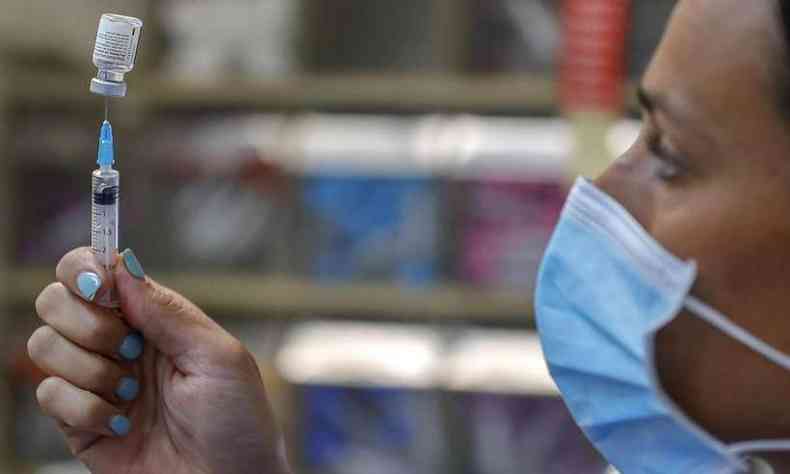 profissional da saúde de máscara segura seringa com vacina contra a covid-19