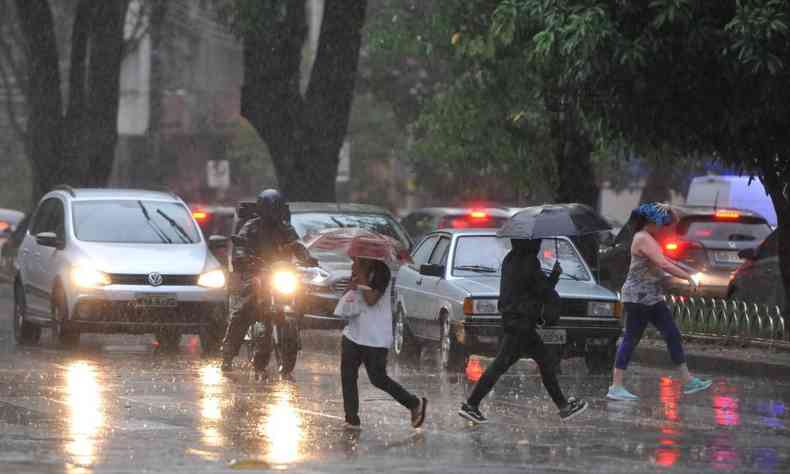 Pessoas atravessando uma rua com guarda-chuva