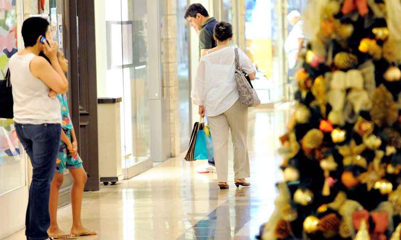 Alta de preços impacta a compra de presentes de consumidores brasileiros neste fim de ano (foto: Gladyston Rodrigues/EM/D.A Press) Com árvore de Natal em primeiro plano, pessoas olham vitrine no corredor de shopping center