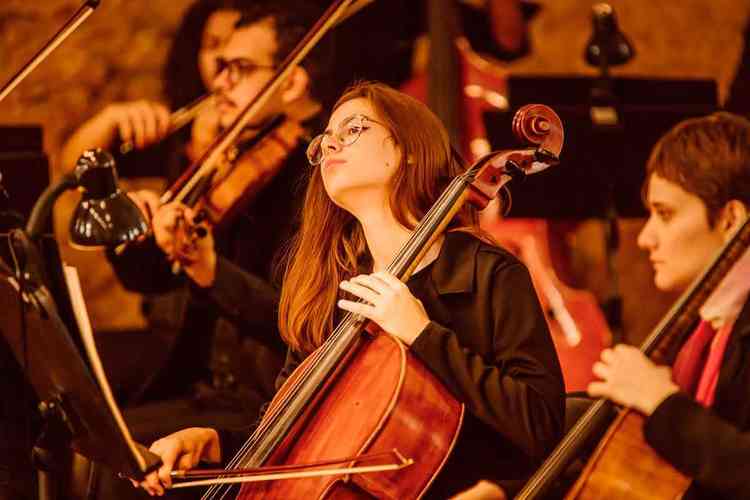 Garota toca violoncelo durante concerto da Academia Orquestra Ouro Preto 