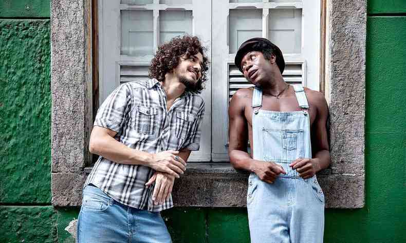 Mrcio Borges (Rmulo Weber) e Milton Nascimento (Tiago Barbosa), de p, apoiados no parapeito de uma janela, se olham em cena de 'Clube da Esquina - Os sonhos no envelhecem'