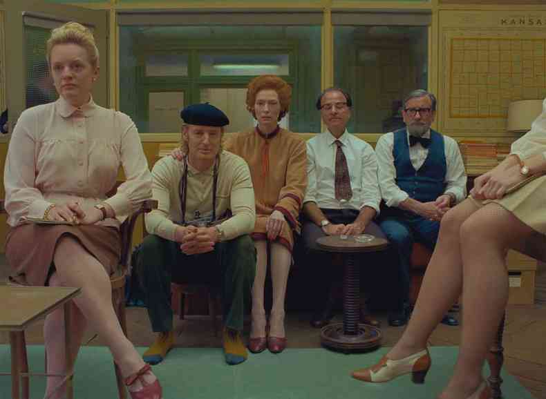 Homens e mulheres olham para a camera, sentados em cadeira e sof, no filme Crnica francesa