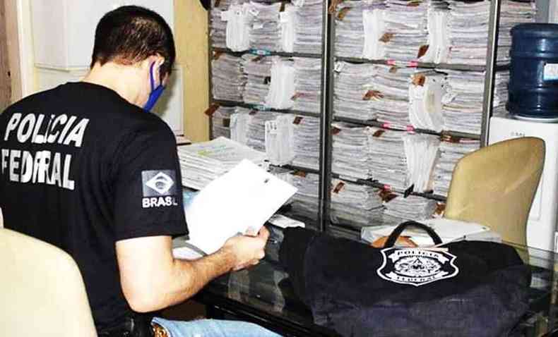 Agente da PF examinando documentos relativos s compras de equipamentos de sade em Coronel Fabriciano(foto: Divulgao Polcia Federal)