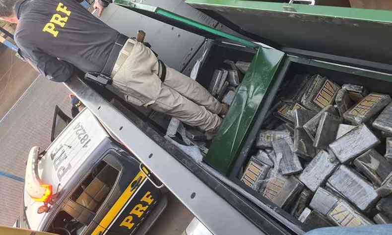 Policial recolhe tabletes da droga em compartimento sobre a carreta(foto: Polcia Rodoviria Federal/Divulgao)