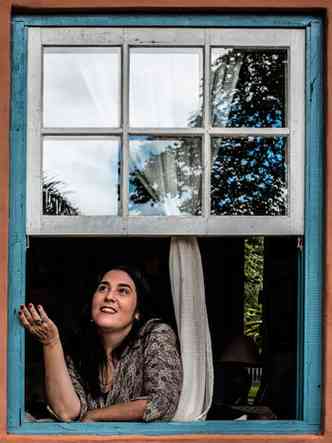 Cantora Mnica Salmaso sorri e olha para o cu, emoldurada por janela de estilo colonial