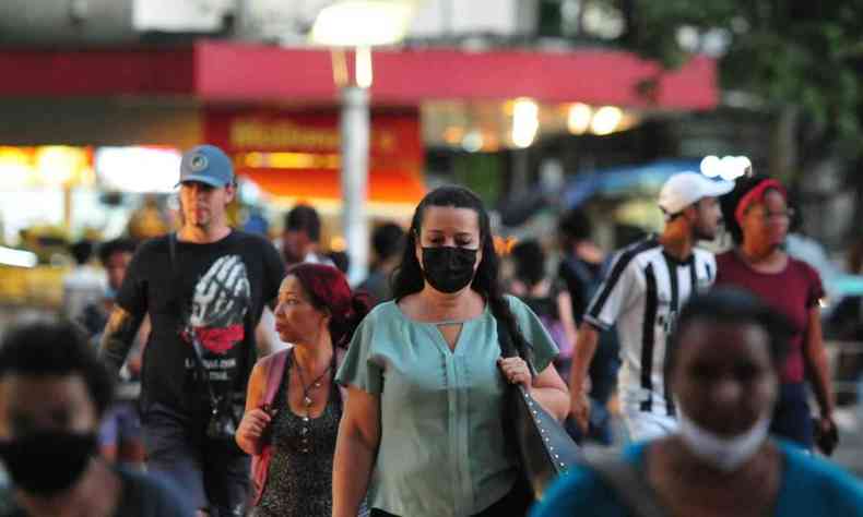 Pessoas na rua com máscara e sem máscara de proteção