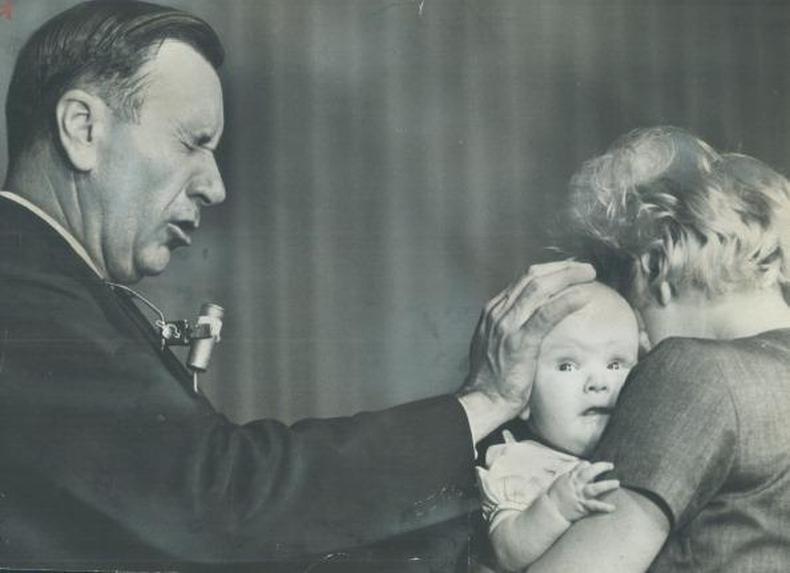 O evangelista americano Oral Roberts (1918-2009), considerado o 'pai' do Evangelho da Prosperidade(foto: Getty Images) O evangelista Oral Roberts com a mãe sobre a cabeça de um bebê, que está no colo da mãe