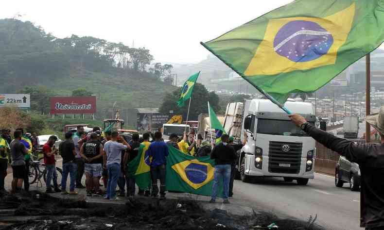Bandeiras do Brasil, caminhes e pessoas em protesto em rodovia